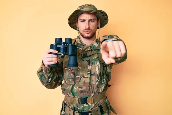 カメラとあなたに指で指して双眼鏡を保持カモフラージュ軍の制服を身に着けている若い白人男性 真剣に見て自信を持ってジェスチャー — ストック写真