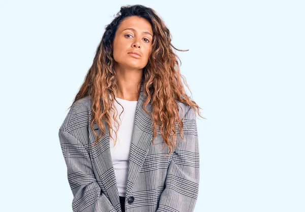 Young hispanic woman with tattoo wearing business oversize jacket relaxed with serious expression on face. simple and natural looking at the camera.