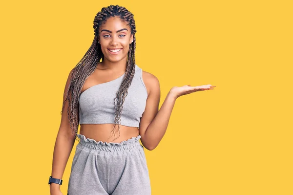 Młoda Afroamerykanka Warkoczami Ubrana Odzież Sportową Uśmiechnięta Pogodna Wskazująca Dłonią — Zdjęcie stockowe
