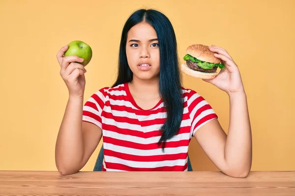 Młoda Azjatka Porównująca Hamburgera Zdrowe Jabłko Bez Pojęcia Zdezorientowana Ekspresja — Zdjęcie stockowe