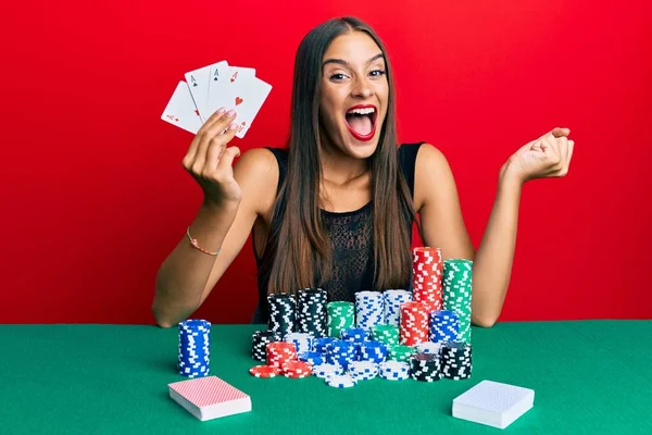Молодая Латиноамериканка Сидящая Столом Играющая Покер Гордыми Картами Празднующая Победу — стоковое фото