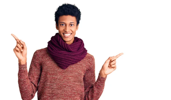 身穿休闲的冬季毛衣和围巾的年轻的非洲裔美国人 带着自信的微笑 用手指指向不同的方向 复制广告空间 — 图库照片