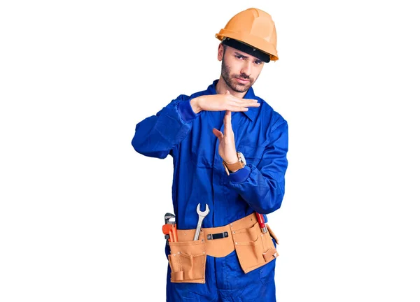 Young hispanic man wearing worker uniform doing time out gesture with hands, frustrated and serious face