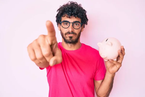 Handsome Young Man Curly Hair Bear Holding Piggy Bank Pointing — Stock Photo, Image