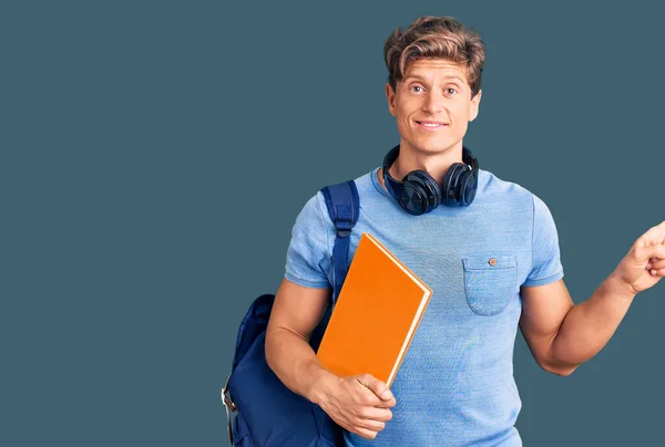 Jovem Homem Bonito Usando Mochila Estudantil Fones Ouvido Segurando Livro — Fotografia de Stock