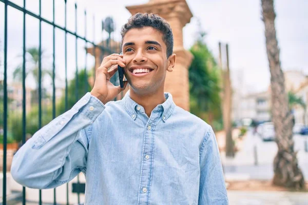 若いラテン語の男笑顔幸せな話上のスマートフォンで街を歩く — ストック写真