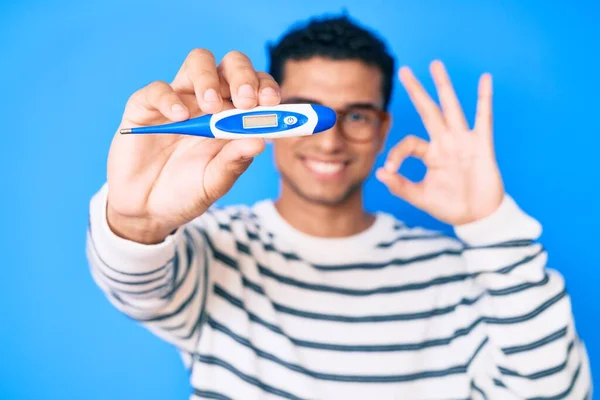 Jovem Homem Hispânico Bonito Segurando Termômetro Fazendo Sinal Com Dedos — Fotografia de Stock