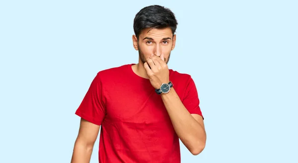 Homem Bonito Jovem Vestindo Camiseta Vermelha Casual Cheirando Algo Fedorento — Fotografia de Stock