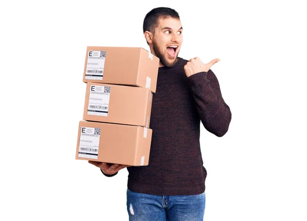 Joven Hombre Guapo Sosteniendo Paquete Entrega Apuntando Pulgar Hacia Lado — Foto de Stock