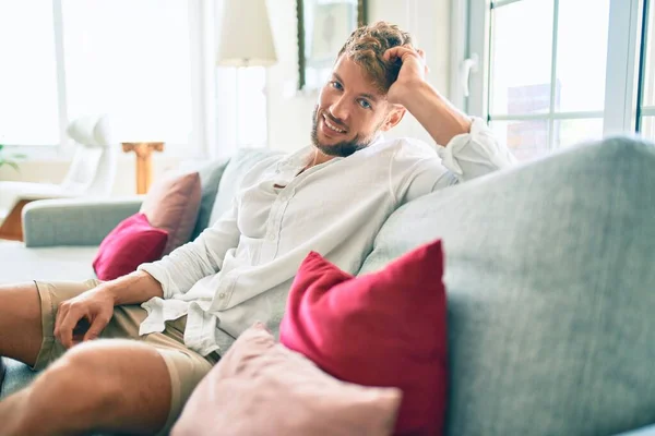 Yakışıklı Beyaz Adam Mutlu Bir Şekilde Gülümsüyor Evdeki Kanepede Oturuyor — Stok fotoğraf