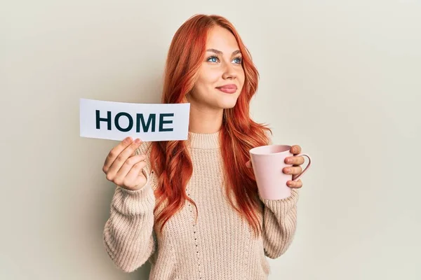 若いですRedhead女性飲むAカップのコーヒーホームテキストを保持笑顔側を見て離れて考え方 — ストック写真