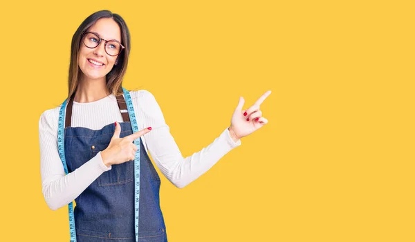 Hermosa Morena Joven Modista Diseñadora Usando Delantal Atelier Sonriendo Mirando —  Fotos de Stock