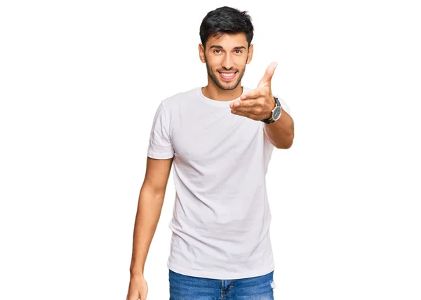 年轻英俊的男子穿着随意的白色T恤 友善地微笑 握手致意和欢迎 成功的商业 — 图库照片