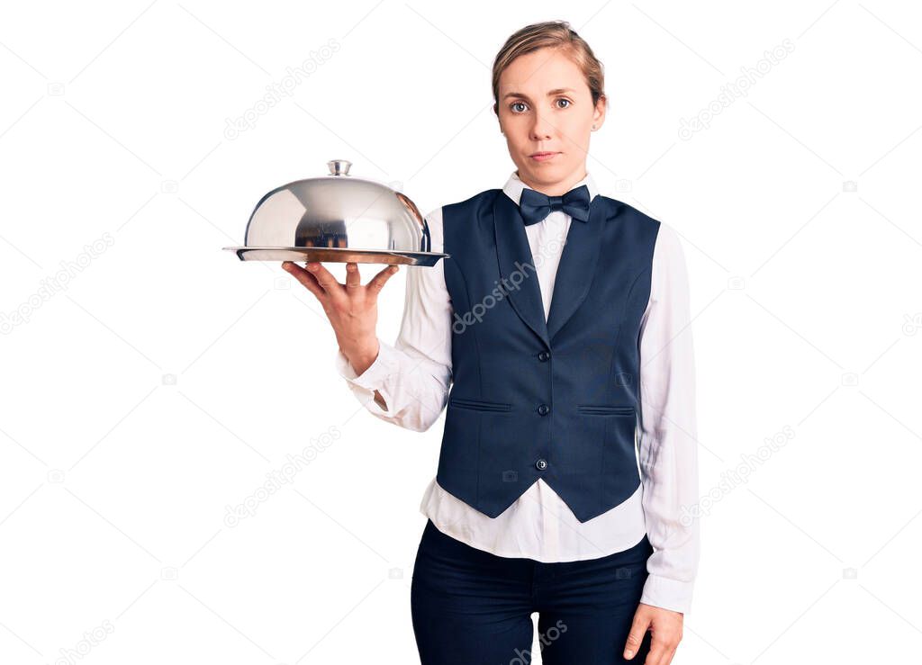 Young beautiful blonde woman wearing waitress uniform holding tray thinking attitude and sober expression looking self confident 