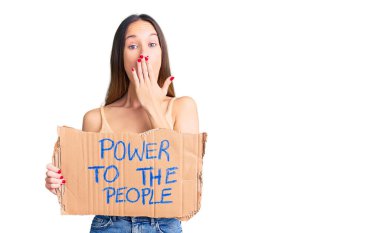 Güzel esmer, genç bir kadın gücü elinde tutuyor. Ağzı eliyle kapatıyor, şok geçiriyor ve hata yapmaktan korkuyor. şaşırmış ifade 