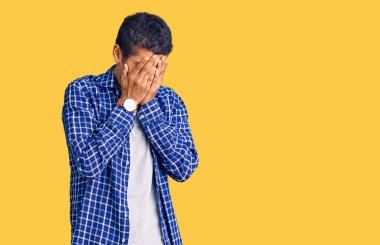 Genç Afro-Amerikan bir adam günlük kıyafetler giyiyor ve ağlarken suratını ellerle kapatıyor. depresyon kavramı. 