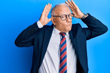 İş elbisesi giyen ve kravat takan beyaz bir adam avuçlarında alaycı ve şüpheci bakışlarla tavşan kulağı hareketi yapıyor. Paskalya tavşanı konsepti. 