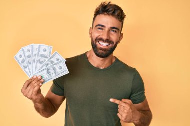 Genç İspanyol adam elinde dolarlarla gülüyor ve kahkahalarla gülüyor.. 