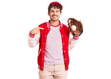 Genç, kıvırcık saçlı, beyzbol forması giyen, elinde Golve ve topuyla gülümseyen mutlu ve gururlu birini işaret eden yakışıklı bir adam. 
