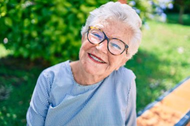 Yaşlı yaşlı, kır saçlı, dışarıda mutlu bir şekilde gülümseyen yaşlı kadın.