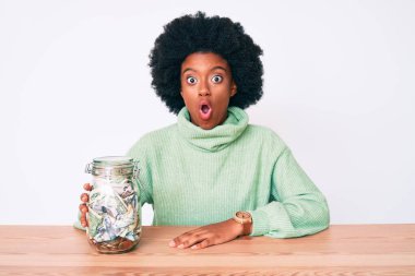 Genç Afro-Amerikalı kadın elinde kavanozla birikimlerini elinde tutuyor. Korkmuş ve şaşırmış bir şekilde ağzı açık bekliyor. 