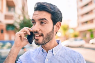Genç İspanyol adam gülümsüyor. Şehirdeki akıllı telefondan konuşuyor..