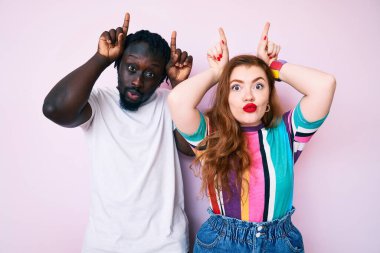 Irklar arası çiftler, günlük kıyafetler giyip parmaklarını boynuzlarına geçirip komik hareketler yapıyorlar. 