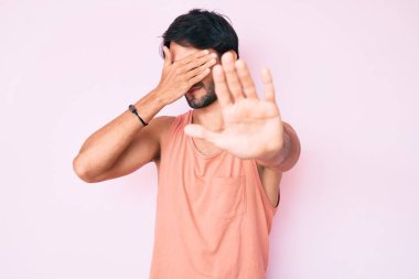 Yakışıklı, günlük kıyafetler giyen, elleriyle gözlerini kapatan, üzgün ve korku ifadeli hareketler yapan İspanyol. utangaç ve olumsuz kavram. 