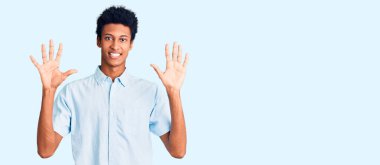 Genç Afro-Amerikalı günlük giysiler giymiş on numarayı gösterip işaret ederken kendinden emin ve mutlu bir şekilde gülümsüyor.. 