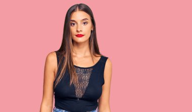 Günlük kıyafetler giyen genç İspanyol kadın yüzünde ciddi bir ifadeyle rahatlamış. Basit ve doğal bir şekilde kameraya bakıyorsun.. 