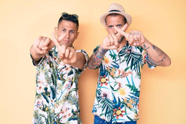 Yaz şapkası takan ve Hawaii tişörtünü reddeden iki genç gay, negatif işaret veriyorlar. 