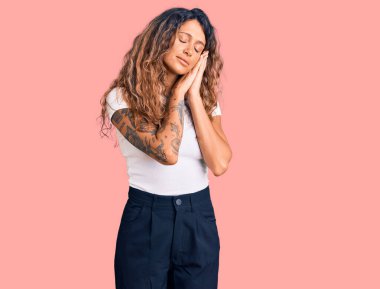 Dövmeli genç, beyaz tişörtlü, yorgun uyuyan, hayal kuran ve elleriyle poz veren, gözleri kapalı İspanyol bir kadın.. 