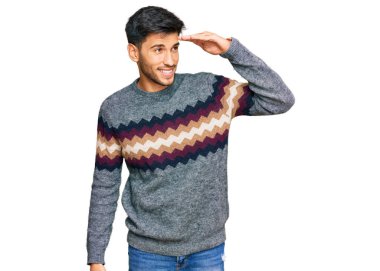 Kış süveteri giyen genç ve yakışıklı bir adam çok mutlu ve gülümseyerek başını kaldırıp uzaklara bakıyor. arama kavramı. 