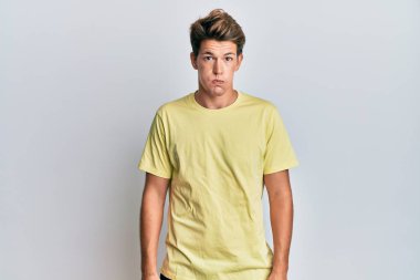 Sıradan kıyafetler giyen yakışıklı beyaz adam komik yüzlü yanakları şişiriyor. Havayla şişmiş ağız, çılgın bir ifade.. 