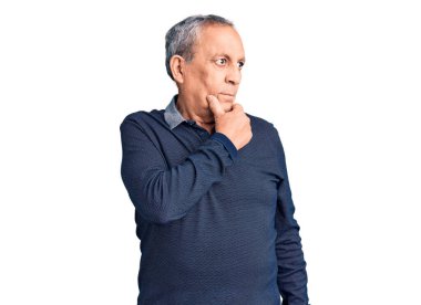 Son sınıf yakışıklısı, elleri çenesinde polo giyen soru soran, düşünceli bir adam. Düşünceli bir yüzle gülümsüyor. şüphe kavramı. 