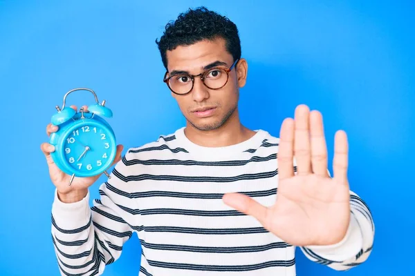 Jovem Homem Hispânico Bonito Segurando Despertador Com Mão Aberta Fazendo — Fotografia de Stock