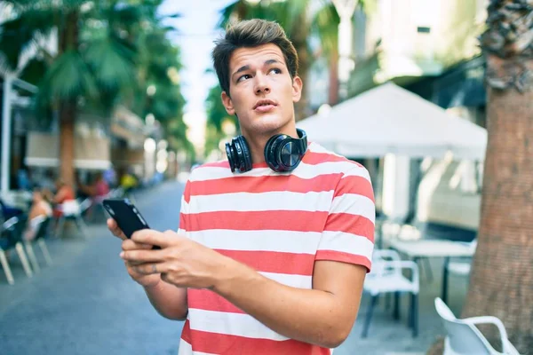 Joven Hombre Caucásico Con Expresión Seria Usando Teléfonos Inteligentes Auriculares — Foto de Stock