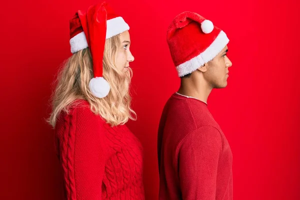 Jovem Casal Interracial Vestindo Chapéu Natal Olhando Para Lado Relaxar — Fotografia de Stock