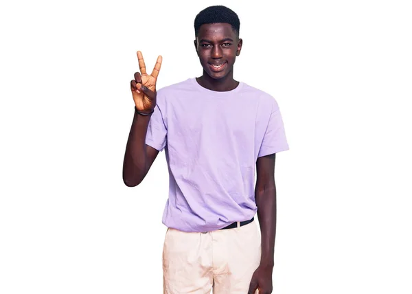自信を持って幸せな笑顔ながら 若いアフリカ系アメリカ人の男性は カジュアルな服を着て指の数2で示すと指摘します — ストック写真