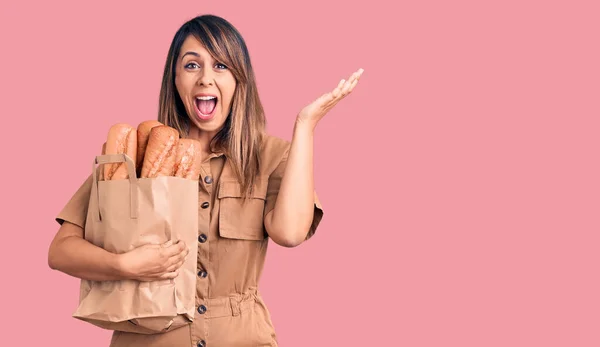 Jovem Bela Mulher Segurando Saco Papel Com Pão Celebrando Vitória — Fotografia de Stock