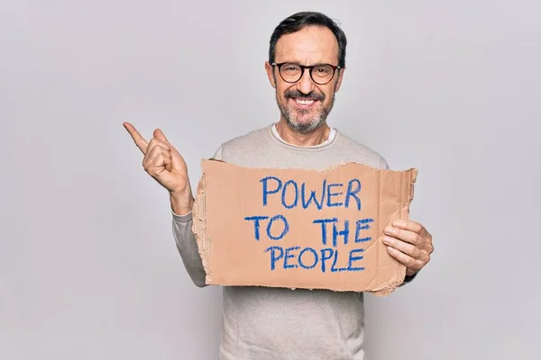 Middle age man asking for social rights holding baner with power to the people message smiling happy pointing with hand and finger to the side