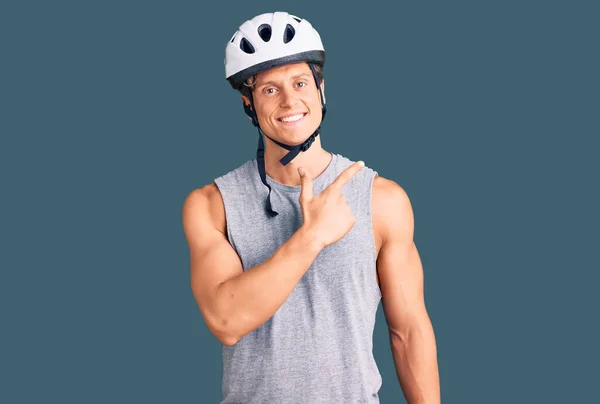 자전거 헬멧을 잘생긴 청년은 얼굴을 가리키며 웃으며 행복하고 스러운 표정으로 — 스톡 사진