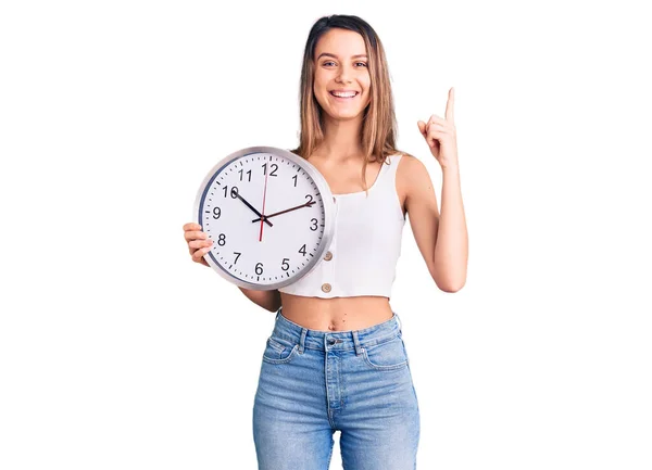 Young Beautiful Girl Holding Big Clock Surprised Idea Question Pointing — Stock Photo, Image