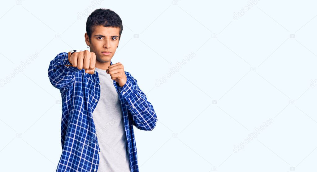 Young african amercian man wearing casual clothes punching fist to fight, aggressive and angry attack, threat and violence 