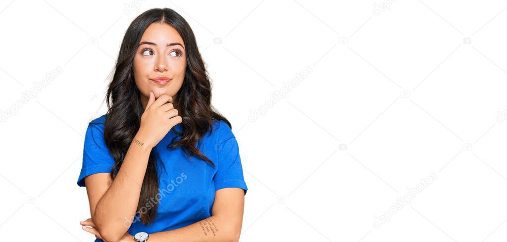Beautiful brunette young woman wearing casual clothes with hand on chin thinking about question, pensive expression. smiling with thoughtful face. doubt concept. 