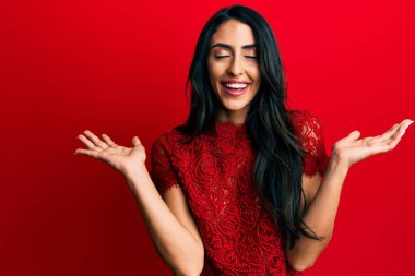 Güzel İspanyol kadın kırmızı arka planda şık kıyafetler giyip başarının çılgınlığını kutluyor kollarını kaldırmış ve gözlerini kapatmış heyecanlı çığlıklar atıyor. Kazanan konsept 