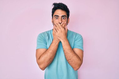 Sıradan kıyafetler giyen yakışıklı, sakallı, ağzı yanlışlıkla elleriyle kapatan bir İspanyol. gizli kavram. 