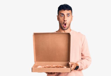 İspanyol genç adam elinde pizza kutusu tutuyor. Korkmuş ve ağzı açık kalmış, şaşırmış ve şaşırmış. 