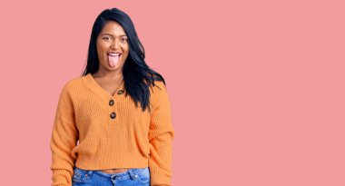 Uzun saçlı, sıradan bir kazak giyen İspanyol kadın komik bir ifadeyle dilini dışarı çıkarıyor. duygu kavramı. 