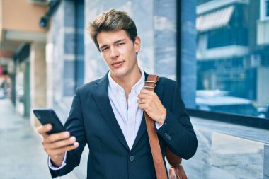 Şehirdeki akıllı telefonu ciddi bir ifadeyle kullanan genç beyaz iş adamı..